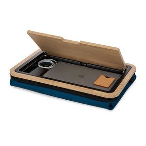Lid of lap desk with navy cushion open at 45 degree angle with storage tray below visible.